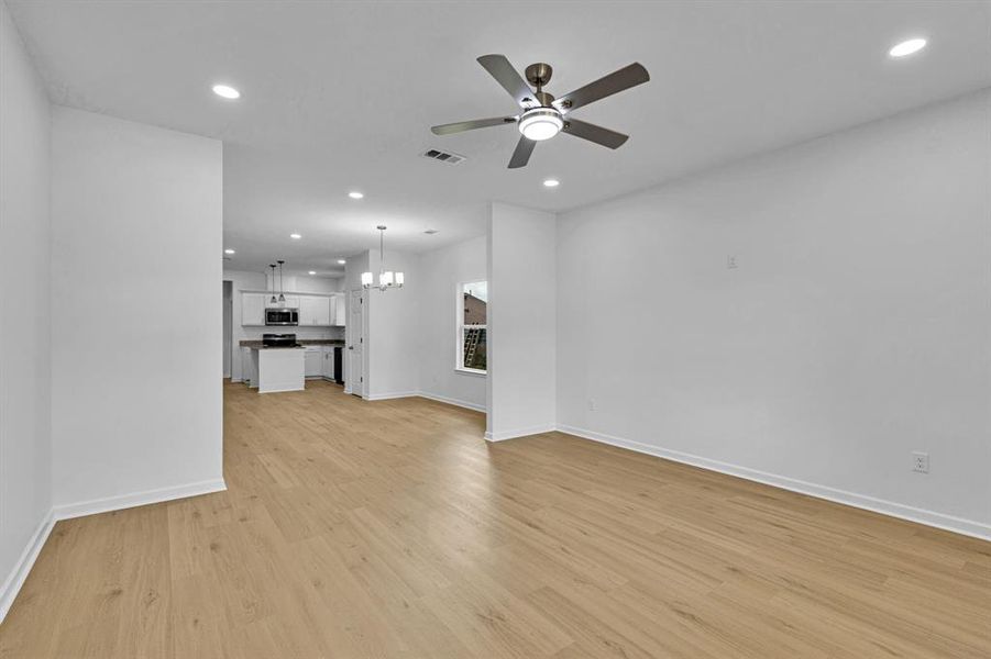 Unfurnished living room featuring light wood-style flooring, a chandelier, recessed lighting, and a ceiling fan Unfurnished living room featuring light wood-style flooring, a chandelier, recessed lighting, and a ceiling fan