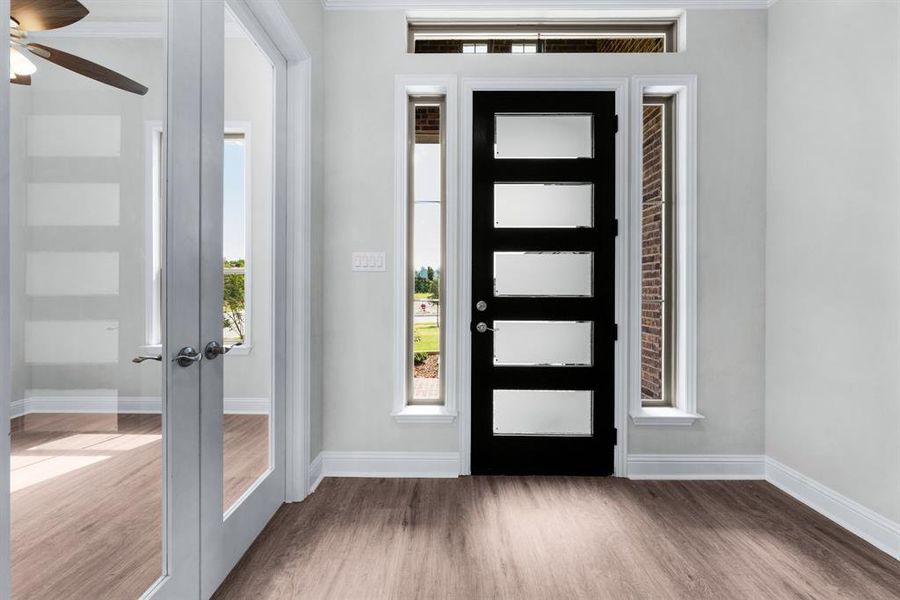 Foyer with a view into the study from the glass french doors featuring luxury vinyl flooring. Foyer with a view into the study from the glass french doors featuring luxury vinyl flooring.