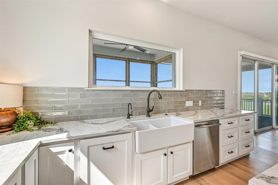 The farmhouse sink overlooks beautiful natural light while custom soft close cabinetry and deep drawers keep everything organized with ease. Sophisticated finishes add warmth and timeless style throughout.