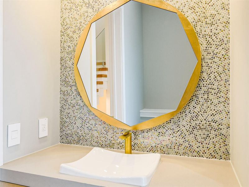 Bathroom vanity with a white vessel sink and a gold-framed mirror