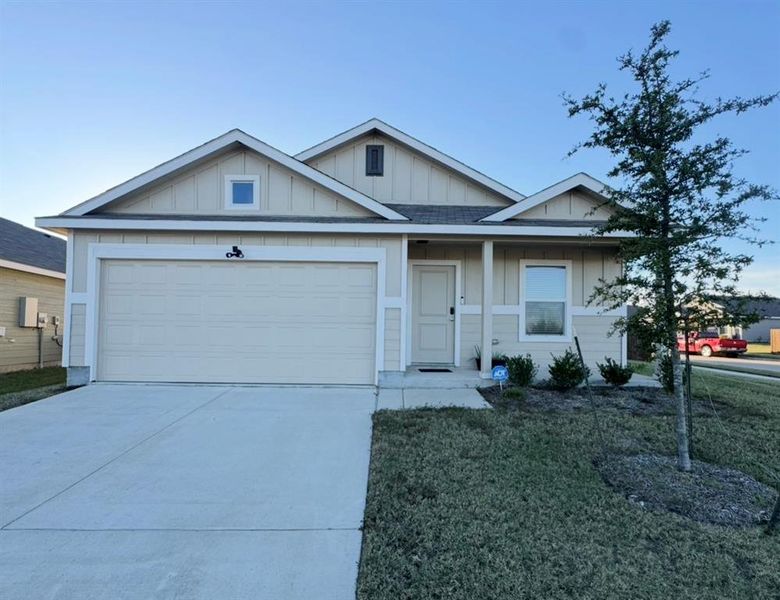 Single story home featuring board and batten siding, concrete driveway, a front lawn, roof with shingles, and a garage