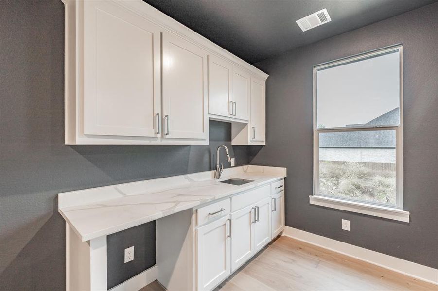 Kitchen featuring white cabinetry, light wood-style flooring, and light stone countertops