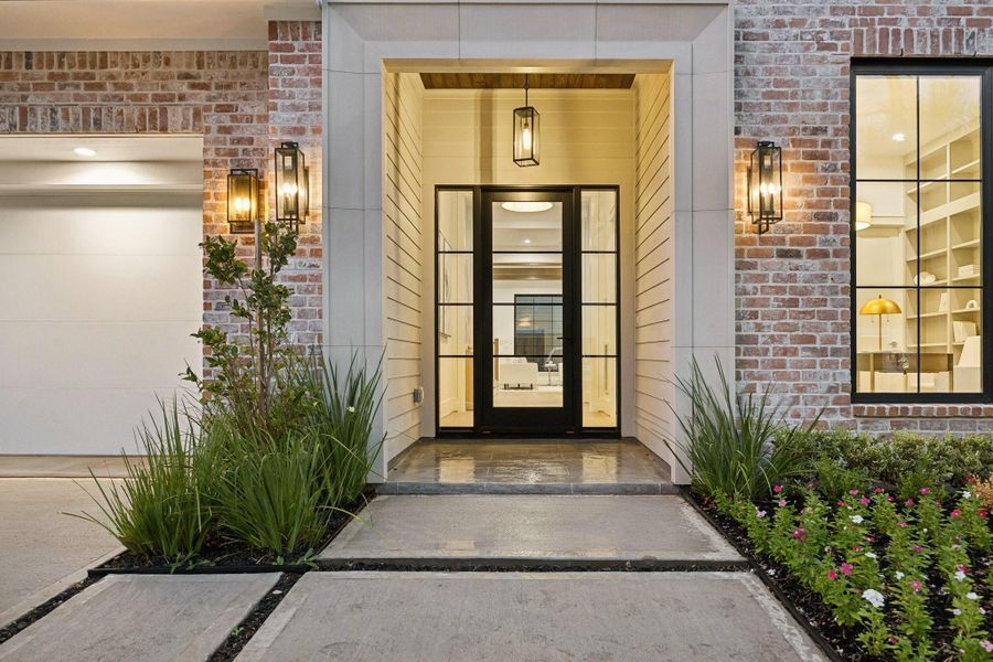 A closer view of the entrance of the home with a Covered Porch, Cast Stone Surround, Tile, Stained Wood Ceiling, Landscaping with full drainage and irrigation. Steel Frame Anderson front door with Sidelights. A closer view of the entrance of the home with a Covered Porch, Cast Stone Surround, Tile, Stained Wood Ceiling, Landscaping with full drainage and irrigation. Steel Frame Anderson front door with Sidelights.