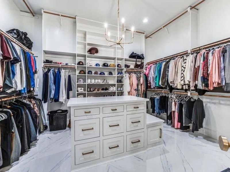 Walk in closet with light marble finish flooring and a chandelier