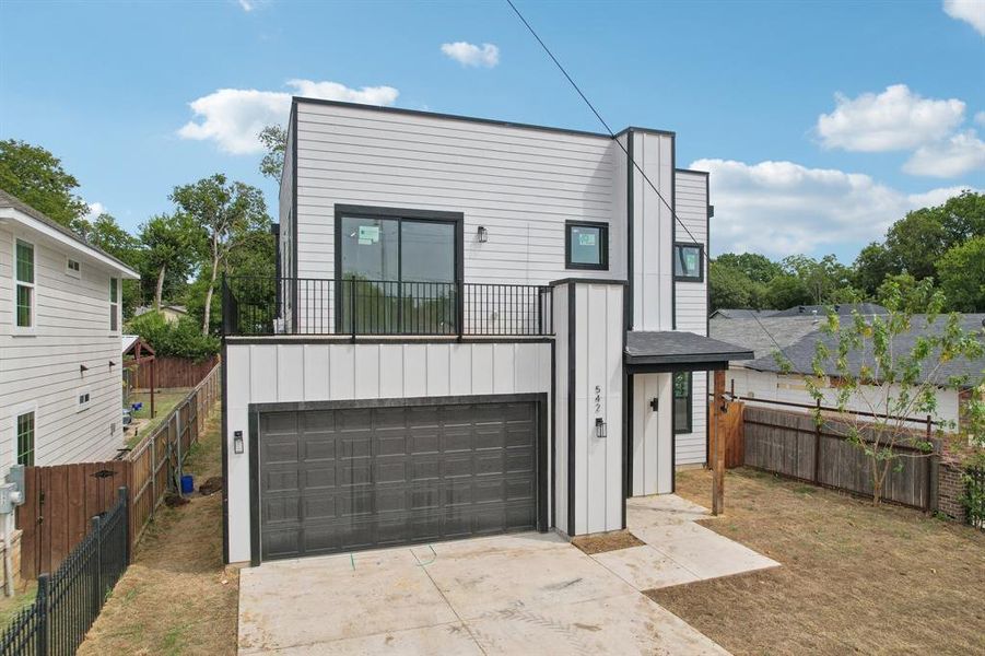 View of front facade featuring a balcony and a garage