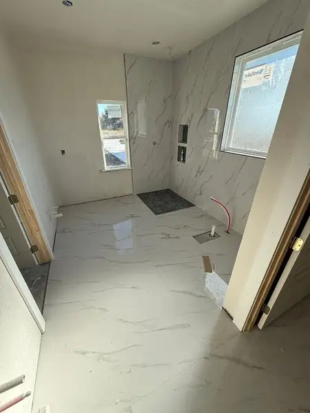 Full bathroom with light marble finish flooring and a marble finish shower Full bathroom with light marble finish flooring and a marble finish shower