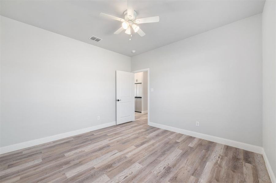 Empty room with ceiling fan and light wood-type flooring