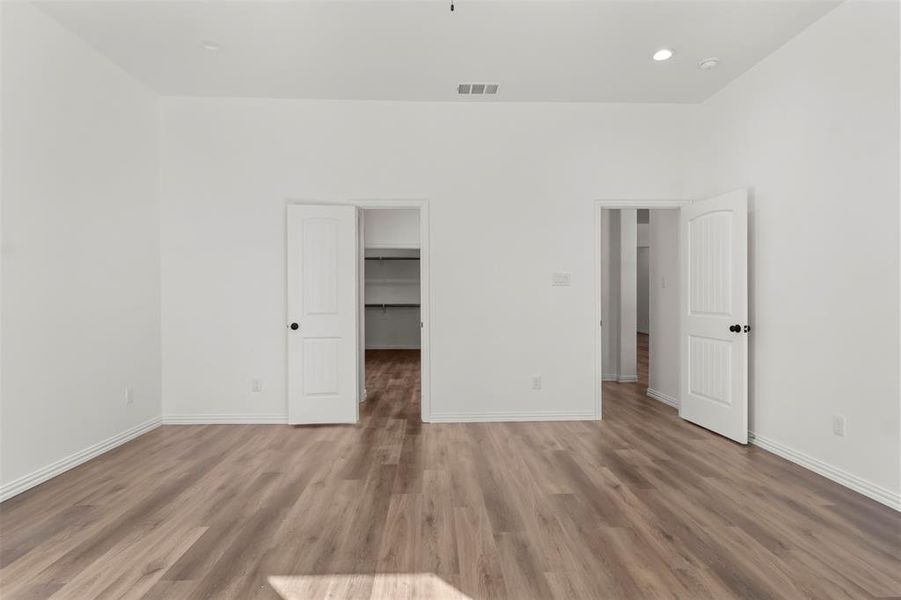 Unfurnished bedroom with wood-type flooring, a walk in closet, and a closet