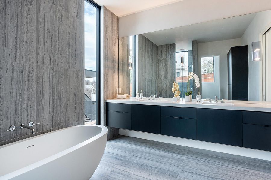 A spacious primary bathroom boasts a freestanding tub, dual vanities, and a floor-to-ceiling window offering city views. A spacious primary bathroom boasts a freestanding tub, dual vanities, and a floor-to-ceiling window offering city views.