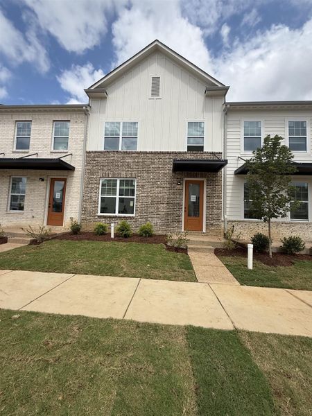 Contemporary townhome exterior featuring a mixed material facade of light brick and white vertical siding Contemporary townhome exterior featuring a mixed material facade of light brick and white vertical siding