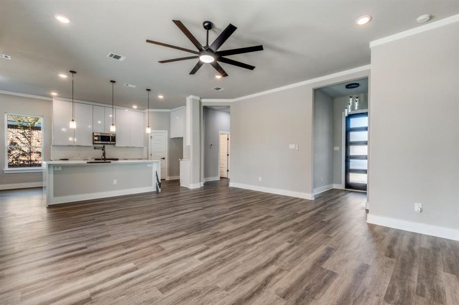 Unfurnished living room featuring crown molding, dark wood-style floors, a ceiling fan, and recessed lighting