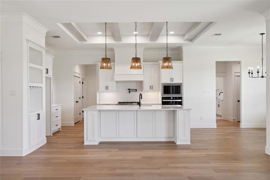 Kitchen with a center island with sink, light hardwood / wood-style floors, white cabinetry, and tasteful backsplash