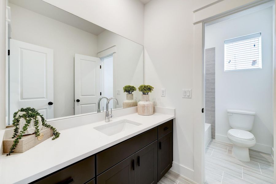 Modern Elegance: This bathroom boasts sleek fixtures, dual vanities, and a spacious walk-in shower, all adorned with contemporary finishes for a serene retreat.