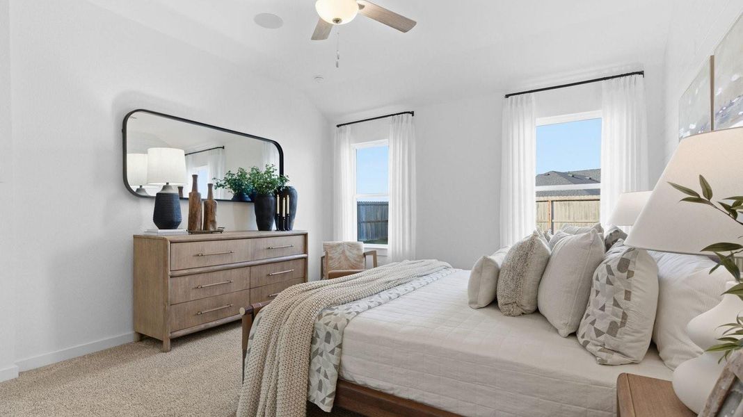Primary bedroom with ceiling fan, plush carpeting, and a large walk-in closet.