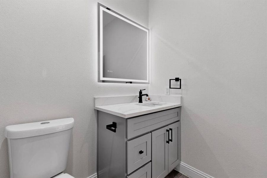 Half bath featuring vanity and a textured wall Half bath featuring vanity and a textured wall
