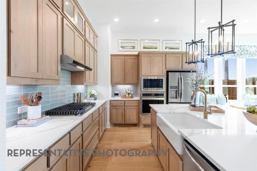 Kitchen with light wood finished floors, decorative backsplash, stainless steel appliances, pendant lighting, and recessed lighting