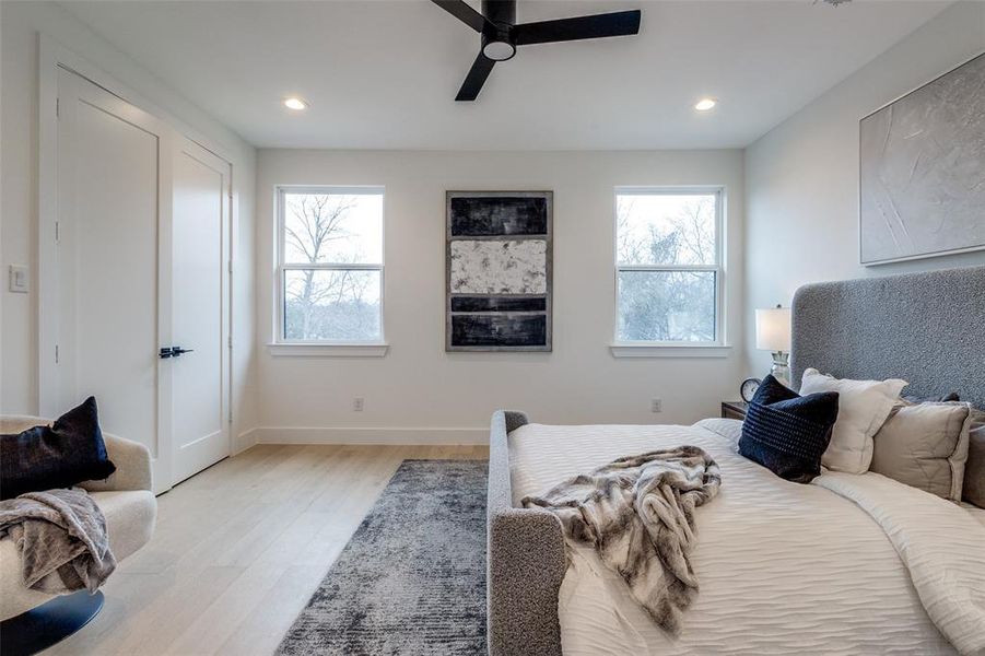 Bedroom featuring ceiling fan, light hardwood / wood-style floors, and multiple windows