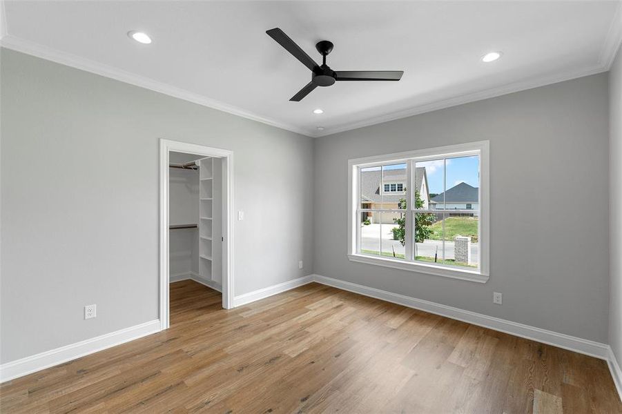 Unfurnished bedroom featuring crown molding, light wood finished floors, a walk in closet, a ceiling fan, and recessed lighting Unfurnished bedroom featuring crown molding, light wood finished floors, a walk in closet, a ceiling fan, and recessed lighting