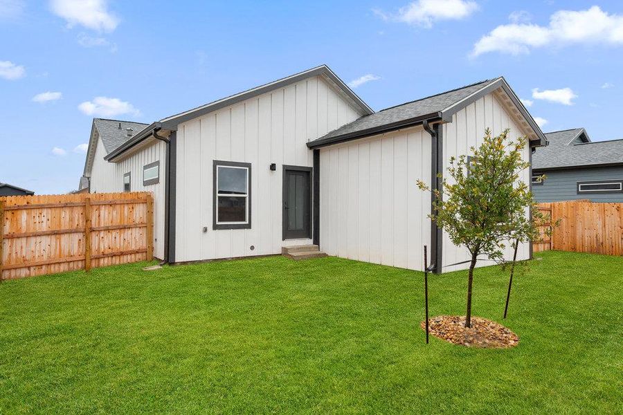 Rear view of property featuring board and batten siding, a fenced backyard, and a shingled roof