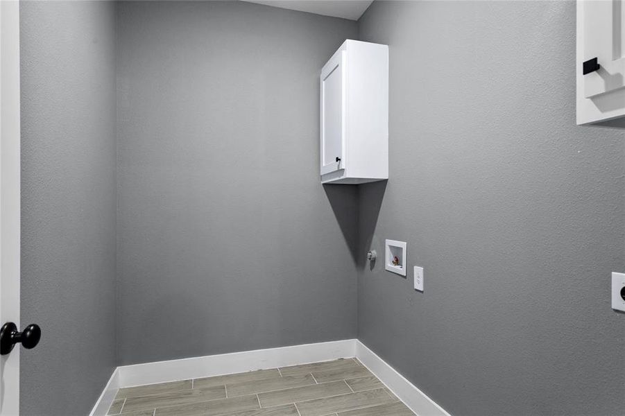 Laundry room with wood finish floors, cabinet space, washer hookup, and hookup for an electric dryer Laundry room with wood finish floors, cabinet space, washer hookup, and hookup for an electric dryer