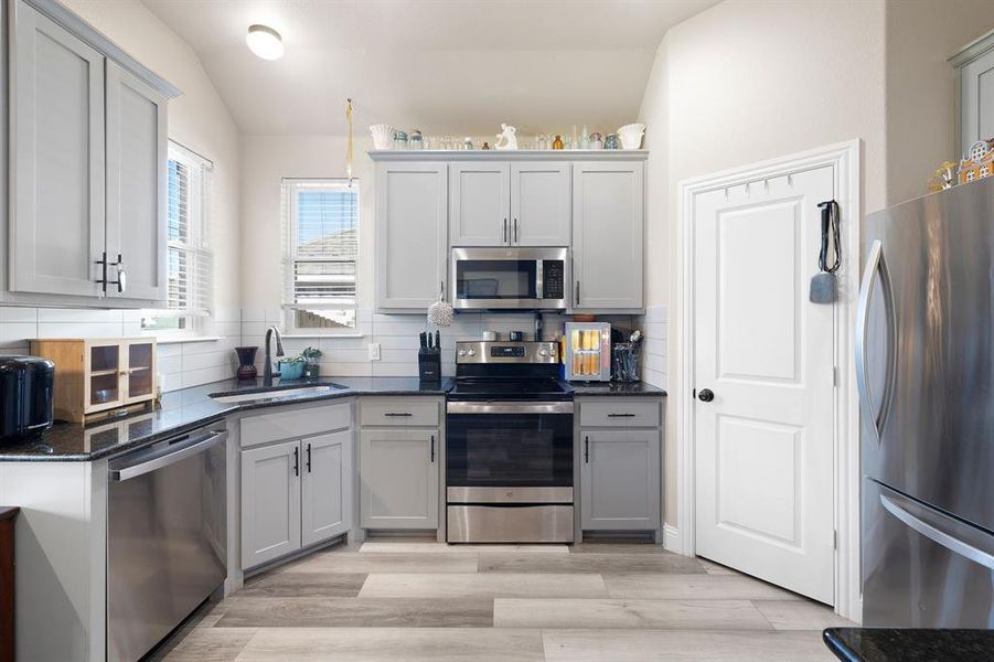 Kitchen featuring decorative backsplash, sink, light hardwood / wood-style flooring, and appliances with stainless steel finishes