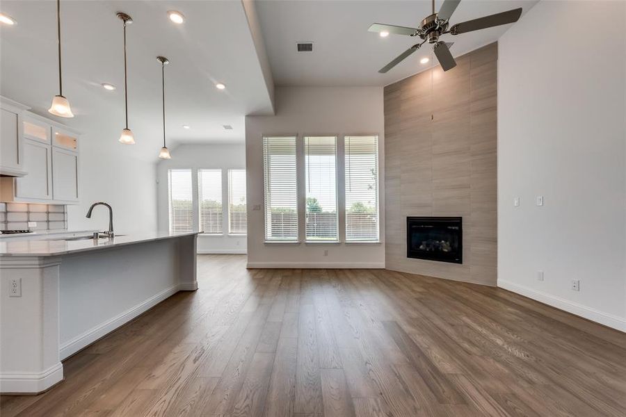 Kitchen with hardwood / wood-style flooring, ceiling fan, a tile fireplace, and white cabinetry