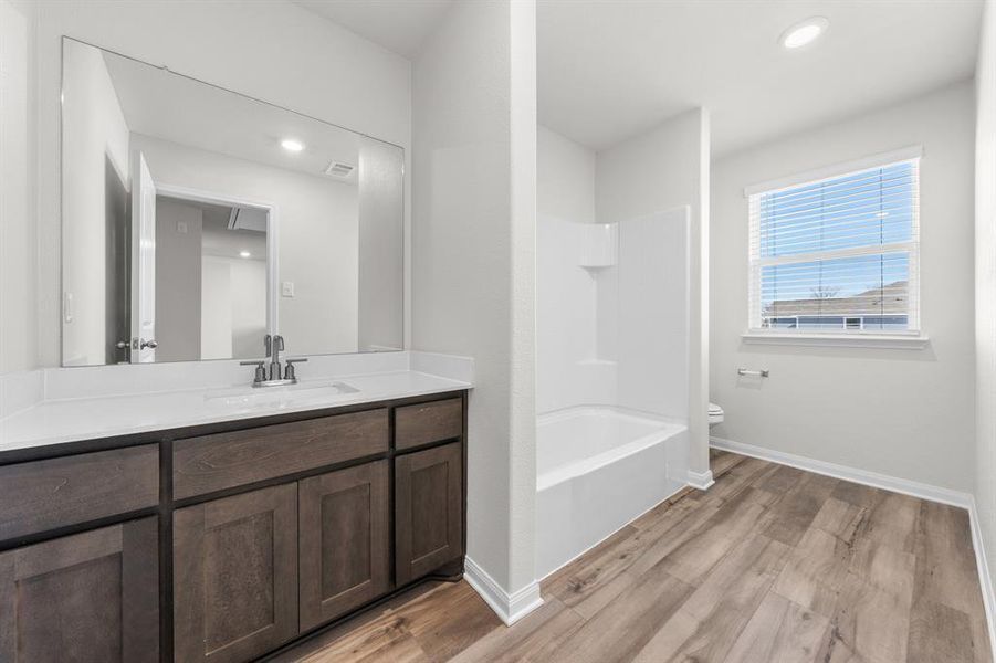 Full bathroom featuring hardwood / wood-style floors, vanity,  shower combination, and toilet