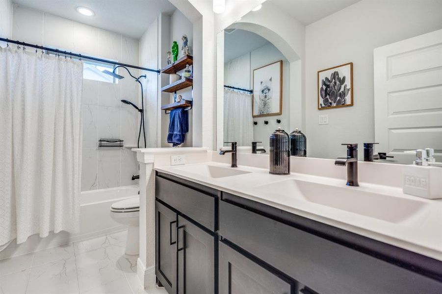 Full bathroom with shower / bathtub combination with curtain, double vanity, and light marble finish floors