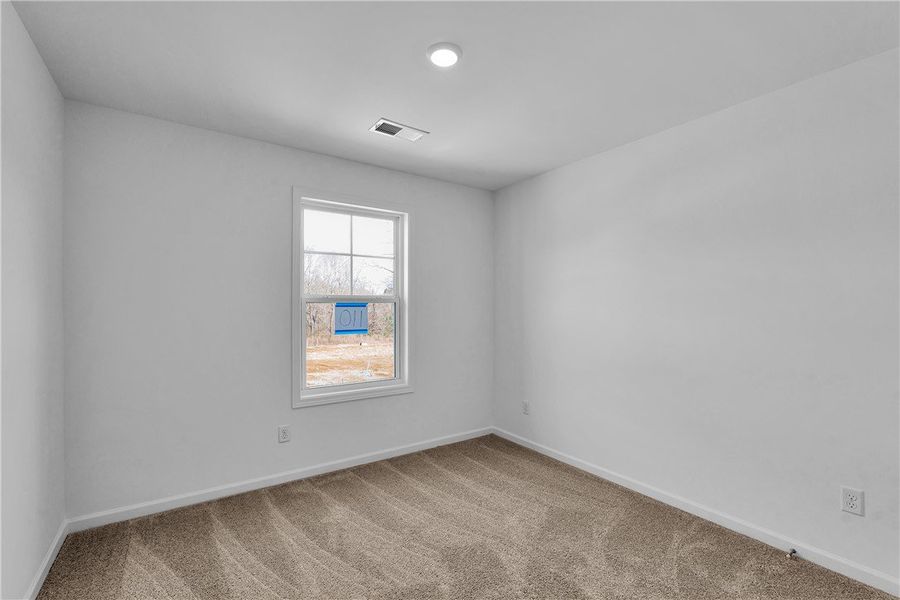 This bright bedroom features a window overlooking This bright bedroom features a window overlooking