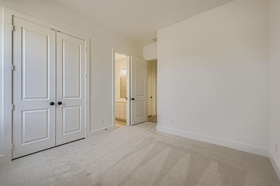 Unfurnished bedroom with carpet floors, ensuite bathroom, and a closet Unfurnished bedroom with carpet floors, ensuite bathroom, and a closet