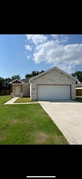 Ranch-style home featuring a two car garage and sodded lawn