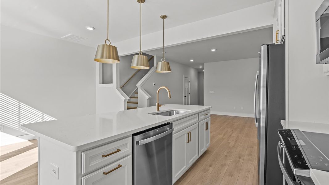 Vibrant and open kitchen centered around a 9-foot island with elegant pendant lighting above