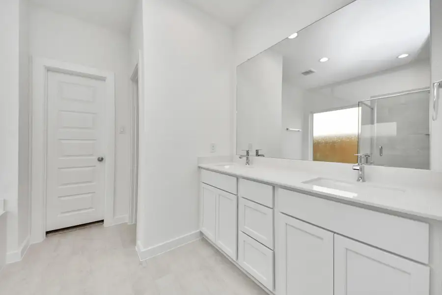 Escape to a spa-like oasis in this primary bathroom. Enjoy a walk-in shower with tile surround, a separate garden tub with custom detailing, and an elegant vanity featuring light countertops, modern hardware, and beautiful recessed lights. Experience luxury and relaxation in every detail.