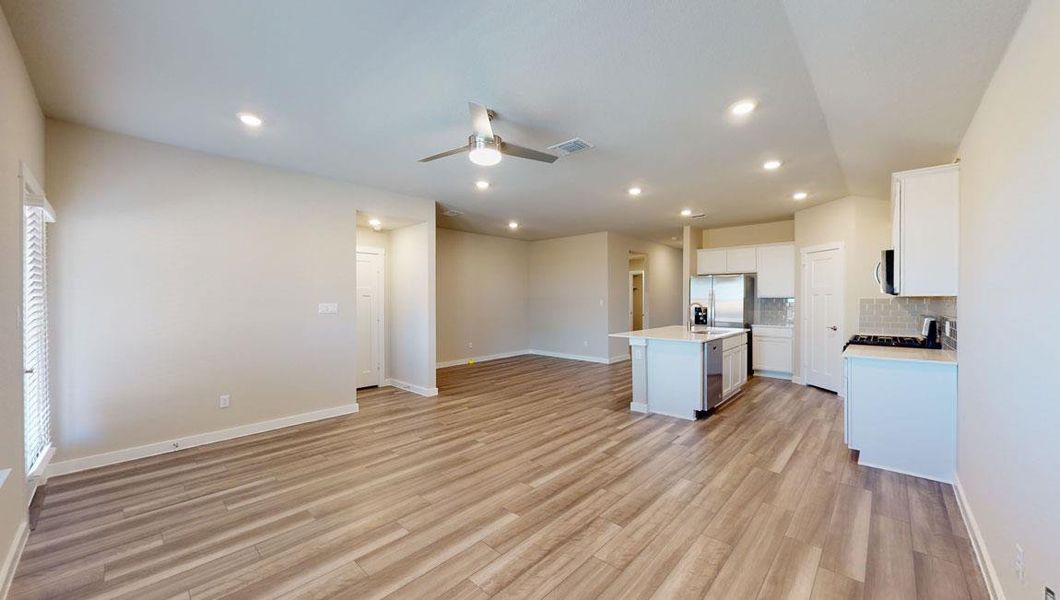 Kitchen featuring open floor plan, stainless steel appliances, a kitchen island with sink, white cabinetry, and light wood-style floors