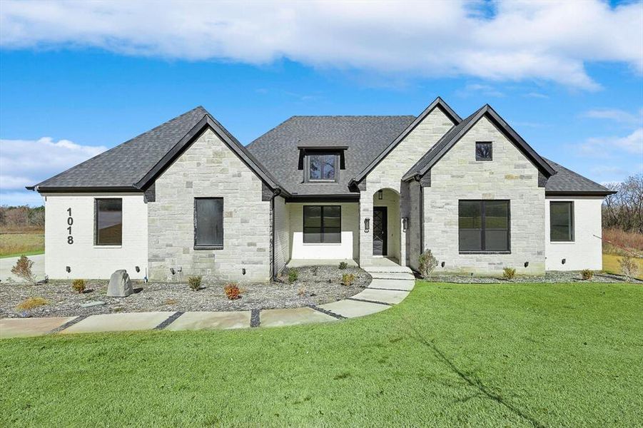 French country inspired facade with a front lawn