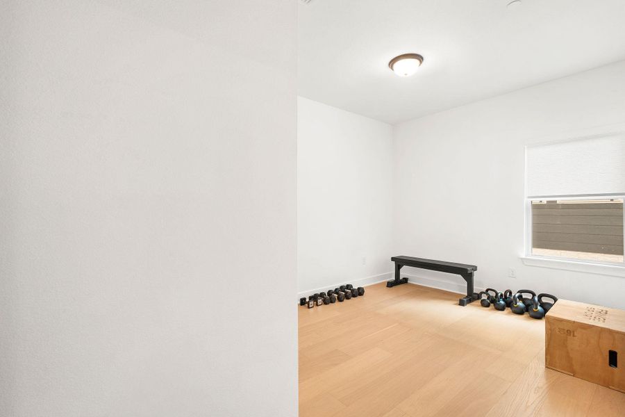 Bright room featuring wood-finish flooring, a contemporary flush-mount ceiling light, and a window with a roller shade Bright room featuring wood-finish flooring, a contemporary flush-mount ceiling light, and a window with a roller shade