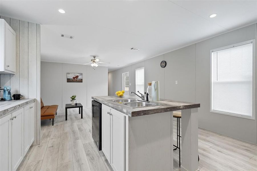 Kitchen with white cabinets, light wood-type flooring, a kitchen breakfast bar, a center island with sink, and recessed lighting Kitchen with white cabinets, light wood-type flooring, a kitchen breakfast bar, a center island with sink, and recessed lighting