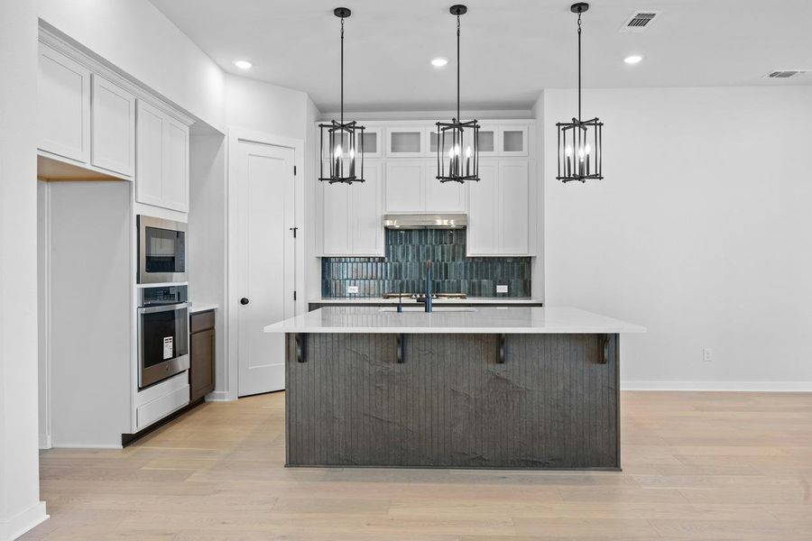 Kitchen featuring a chandelier, decorative backsplash, light countertops, and recessed lighting Kitchen featuring a chandelier, decorative backsplash, light countertops, and recessed lighting