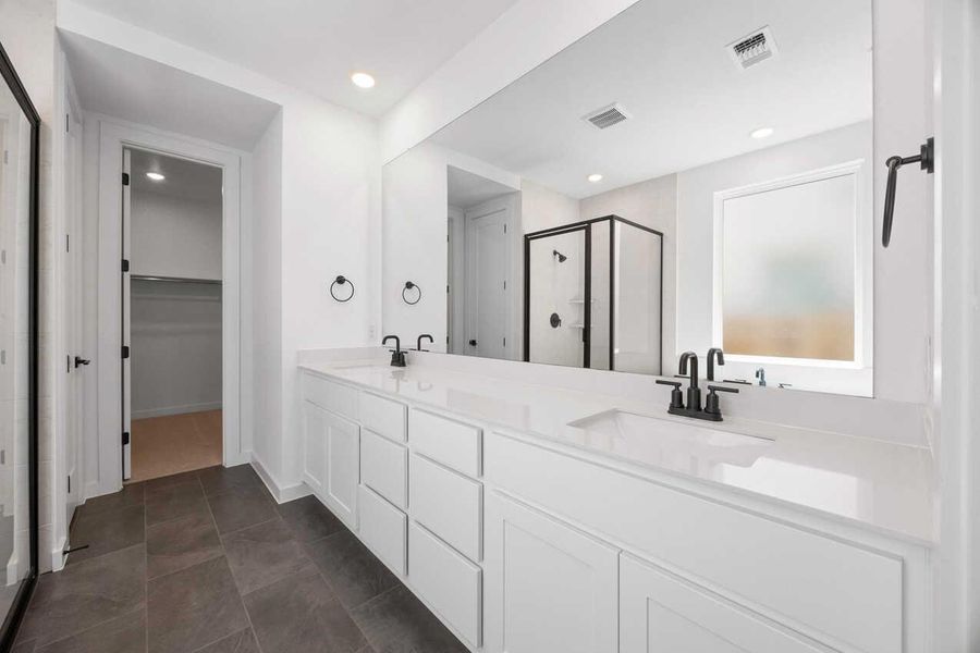 Bathroom featuring a shower stall, double vanity, a spacious closet, dark tile patterned flooring, and recessed lighting Bathroom featuring a shower stall, double vanity, a spacious closet, dark tile patterned flooring, and recessed lighting