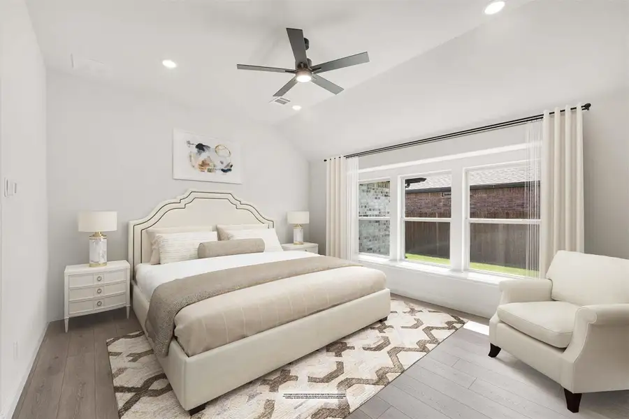 Bedroom with vaulted ceiling, ceiling fan, hardwood floors, and large windows with neutral furnishings Bedroom with vaulted ceiling, ceiling fan, hardwood floors, and large windows with neutral furnishings