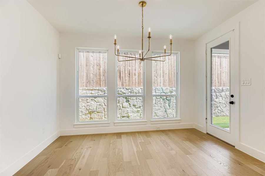 Unfurnished dining area with a chandelier and light wood-style flooring