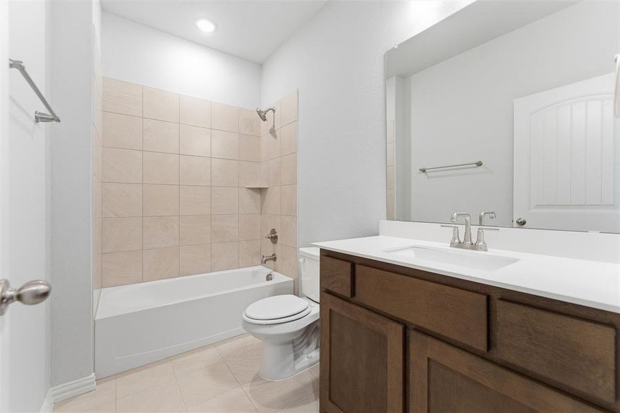 Bathroom with washtub / shower combination, vanity, and light tile patterned floors