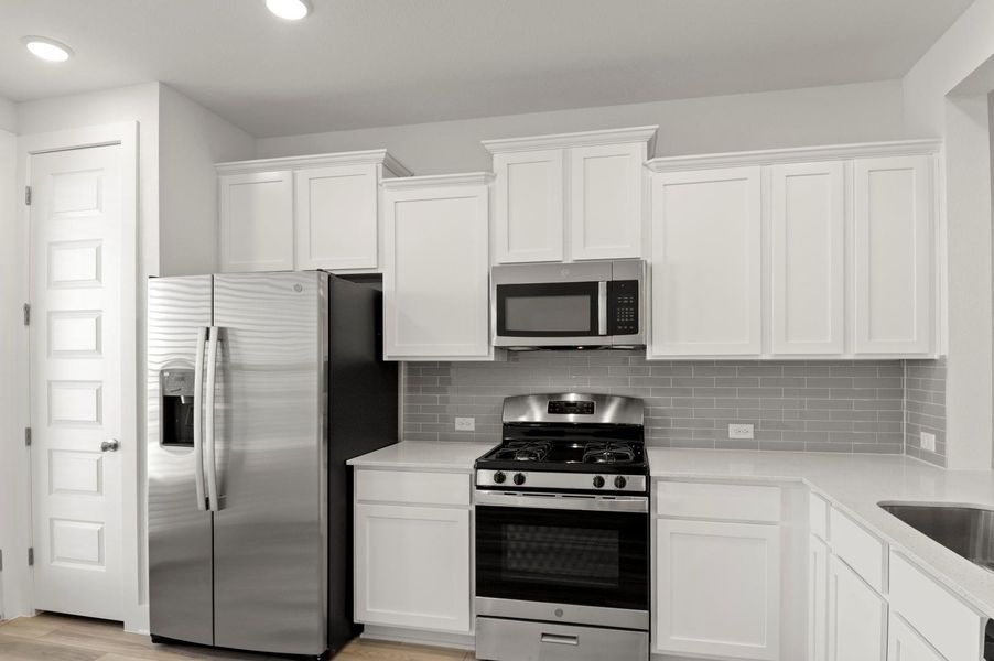 Kitchen featuring appliances with stainless steel finishes, white cabinetry, light stone countertops, tasteful backsplash, and recessed lighting