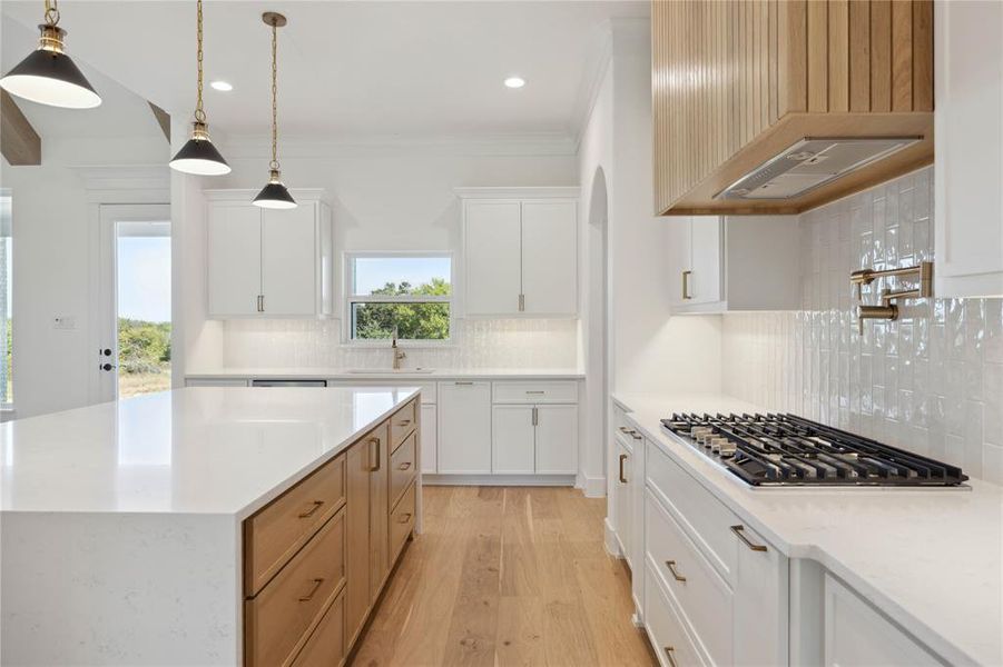 Kitchen featuring white cabinetry, stainless steel gas cooktop, pendant lighting, and tasteful backsplash