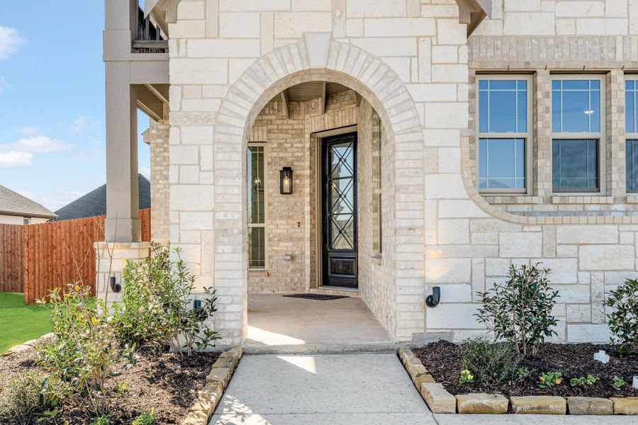 Home entrance with stone arch, black front door, and landscaped walkway