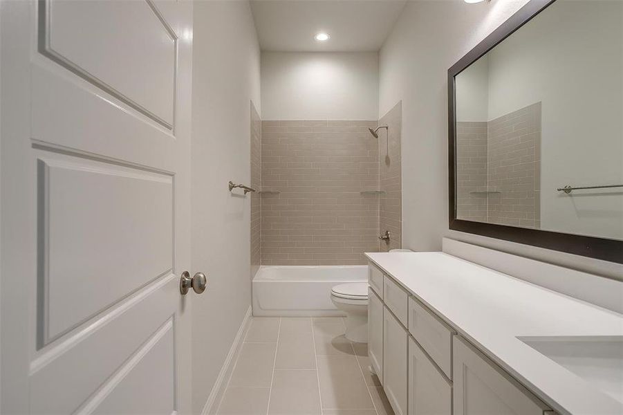 Full bathroom featuring tile patterned floors, tiled shower / bath, vanity, and toilet