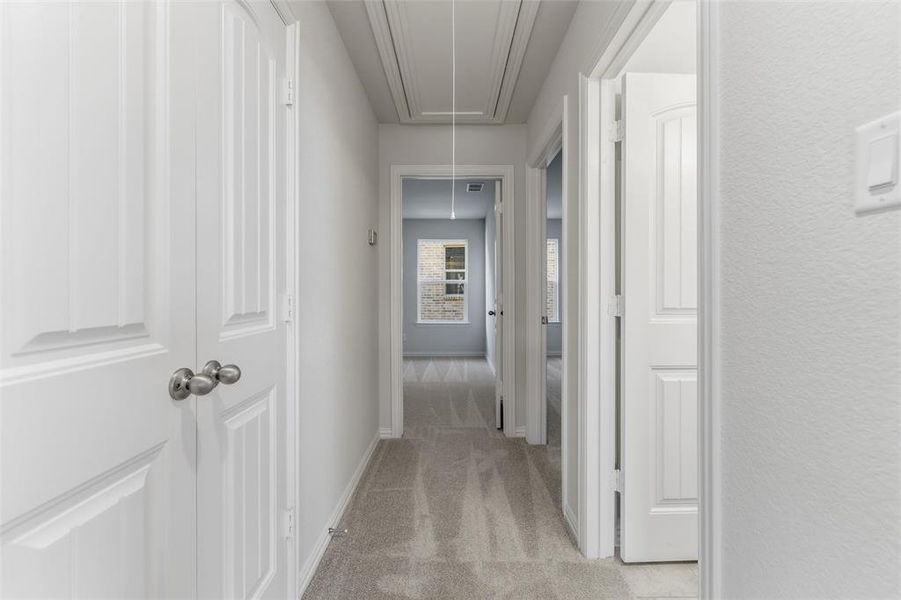 Hallway featuring attic access and light colored carpet