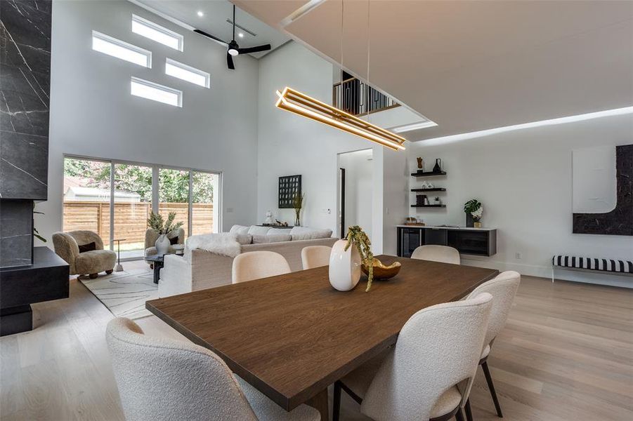 Dining room with wood-type flooring, a towering ceiling, and ceiling fan