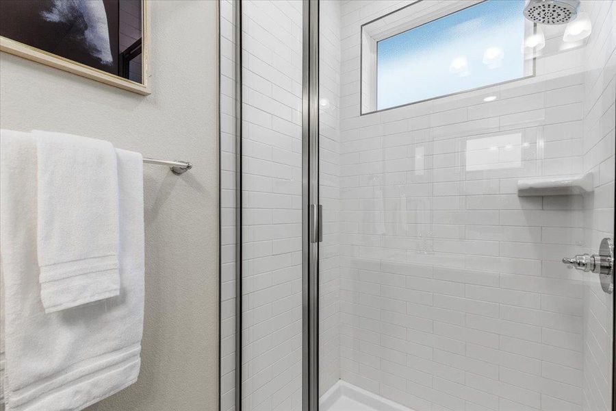 The spacious walk-in shower features subway tile and a window for natural light.