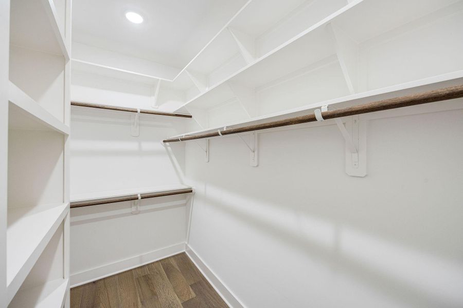 Large walk-in primary bedroom closet with built-in shelving